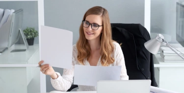 Frau schaut auf ein Blatt Papier und lächelt