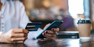 Bezahlen Sie Waren mit Kreditkarte über ein Smartphone in einem Café