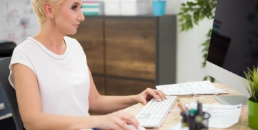 Frau arbeitet am Schreibtisch mit Tastatur und Maus