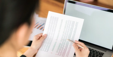Business woman hand with financial charts and laptop on the table