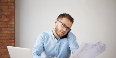 Mann sitzt im Büro am Schreibtisch und telefoniert