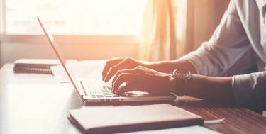 Mann tippt auf einem Laptop