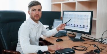 mann am schreibtisch mit rechner im Büro und erklärt Zahlen