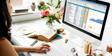 Frau, die am Schreibtisch sitzt und an einer Excel-Tabelle arbeitet