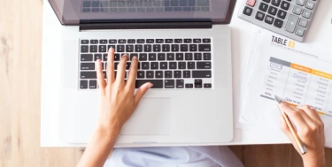 Person tippt auf dem Laptop am Schreibtisch