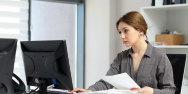 Eine Frau sitzt im Büro am Rechner und tippt etwas