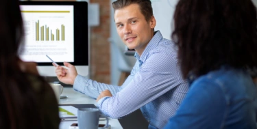 Mann im Meeting erklärt Zahlen am Bildschirm