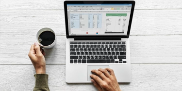 Person mit Laptop und Kaffeetasse