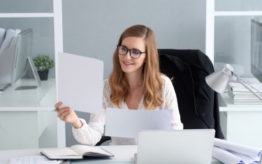 Frau schaut auf ein Blatt Papier und lächelt