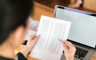 Business woman hand with financial charts and laptop on the table