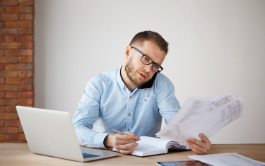 Mann sitzt im Büro am Schreibtisch und telefoniert
