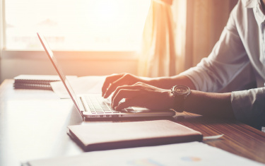 Mann tippt auf einem Laptop