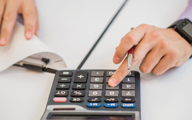 Close-up von Geschäftsmann Berechnung Rechnungen mit Taschenrechner 