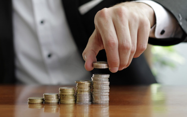 Nahaufnahme der Hände eines Geschäftsmannes, der nach dem Geschäftserfolg Münzstapel zählt