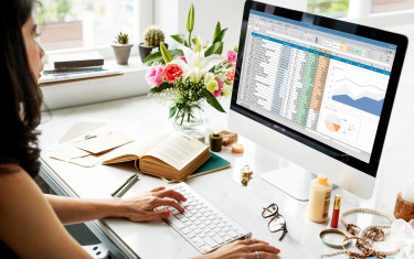 Frau, die am Schreibtisch sitzt und an einer Excel-Tabelle arbeitet