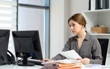 Eine Frau sitzt im Büro am Rechner und tippt etwas 