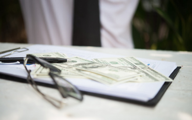 Geldscheine liegen auf ein Blatt Papier und daneben eine Brille