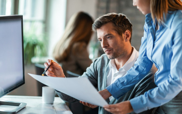 Zwei Geschäftspartner prüfen gemeinsam Dokumente im Büro